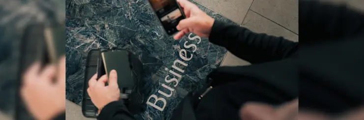 Phone and passport with suitcase above floor reading 'business'