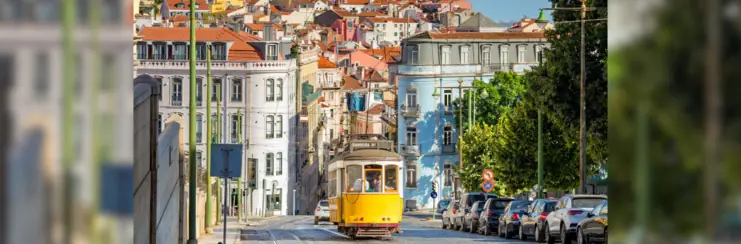Yellow tram in Lisbon with city behind it