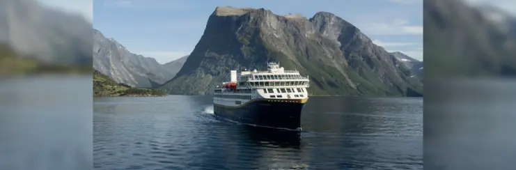 Havila ship sailing with mountain behind it