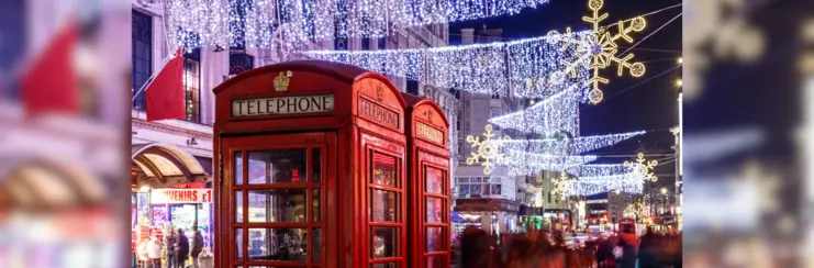 Red telephone box in London at night with Christmas lights