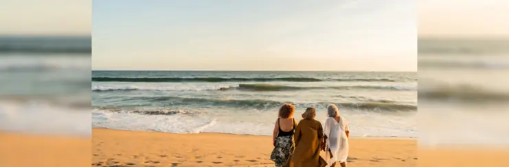 Three women on the beach facing out to the sea