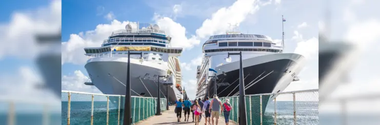 Two cruise ships at a dock, people walking towards them to board