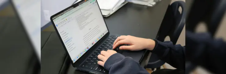 Laptop on desk with hands typing
