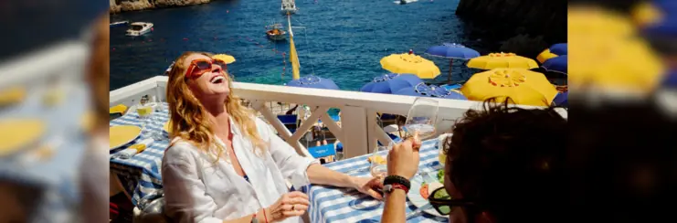 Woman laughing at table overlooking the sea in Capri