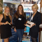 Emma Colyer (left) from Air Mauritius and Sharon Jones (right) from Sunset Faraway present Laura Clarke from Global Independent Travel with her prize - a bottle of Champagne and a box of chocolates.